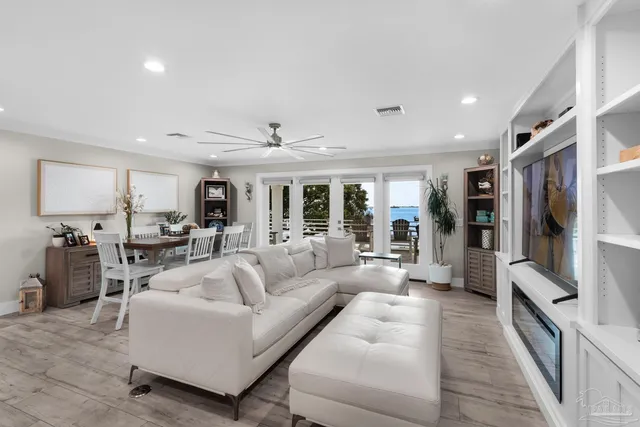 a dining hall with stainless steel appliances kitchen island granite countertop a dining table chairs and a refrigerator