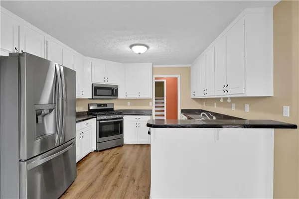 a kitchen with granite countertop a refrigerator stove and microwave