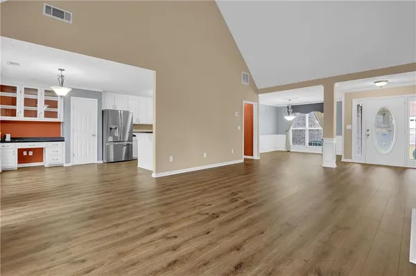 a view of a kitchen with a fridge and wooden floor