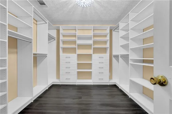 a view of an empty room with wooden floor and closet