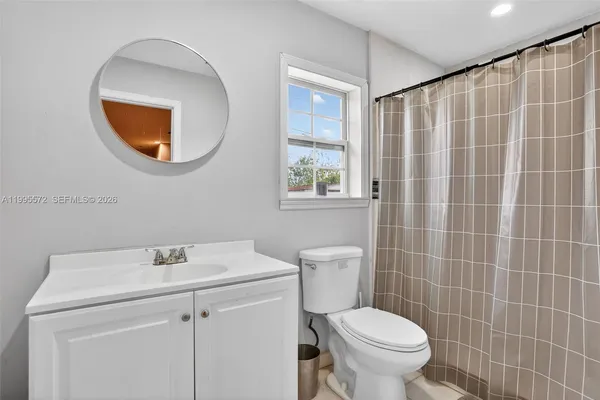 a bathroom with a toilet a sink a mirror and a window