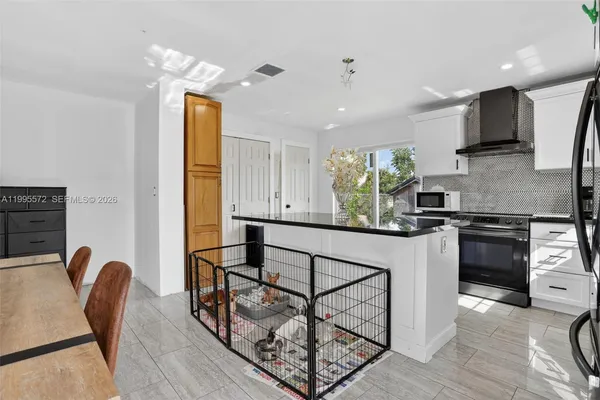 a kitchen with stainless steel appliances granite countertop a stove top oven a sink a dining table and chairs with wooden floor