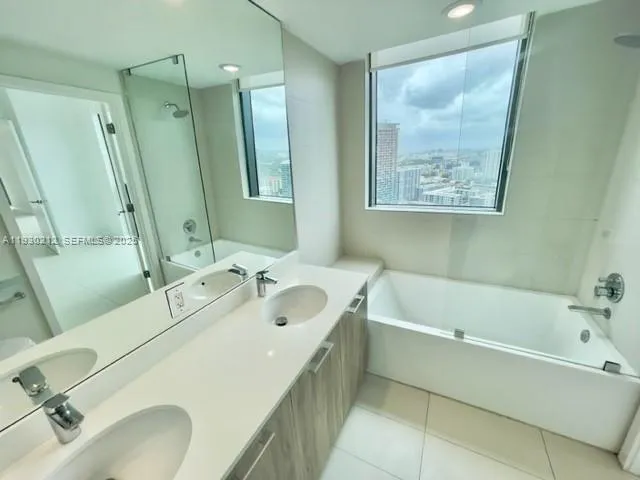 a bathroom with a tub sink and mirror