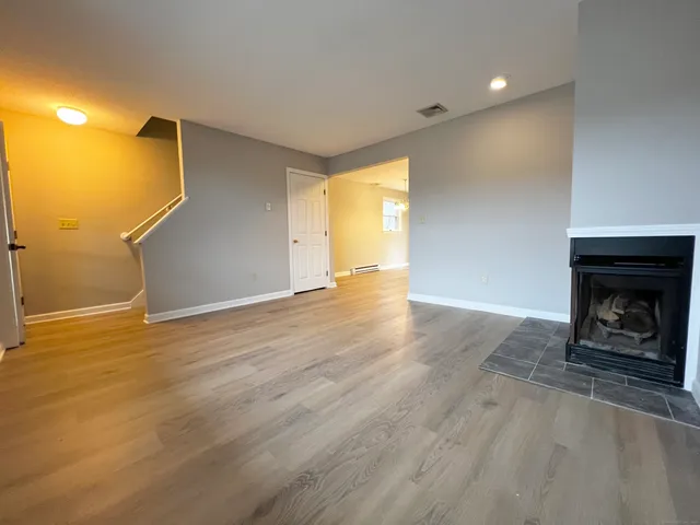 a view of an empty room with wooden floor and a fireplace