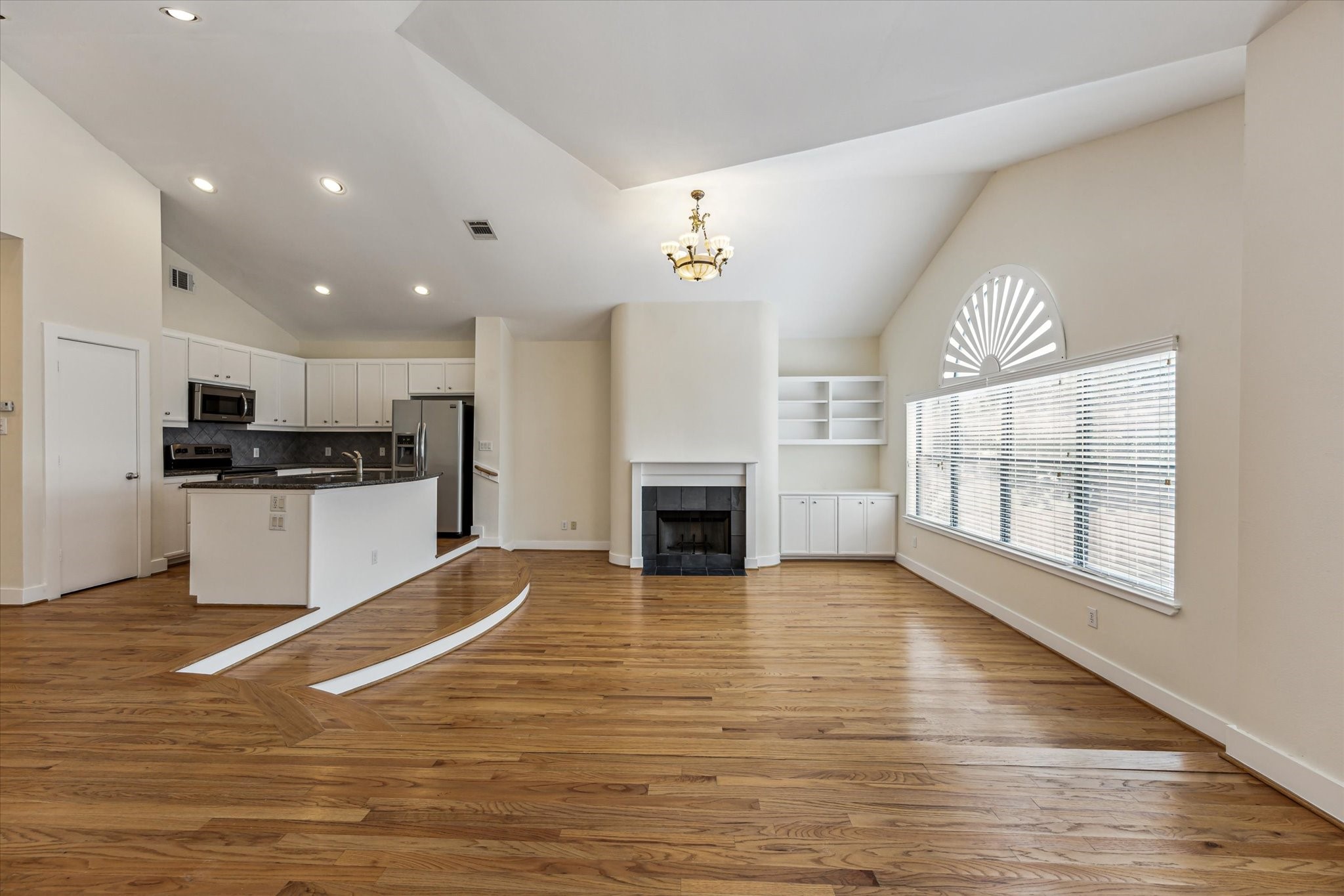9829 Riddlelink Lane Houston, TX 77025 - Photo 5 of 22 Elegant flow from the living area to the kitchen, highlighted by a gas fireplace and built-in cabinetry.