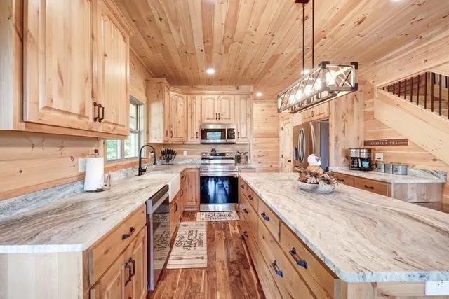 a kitchen with stainless steel appliances granite countertop a sink a stove and a wooden cabinets
