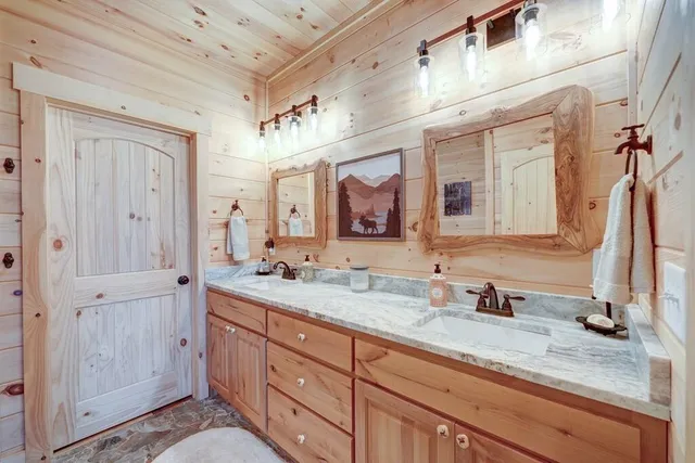 a bathroom with a granite countertop double vanity sink and mirror