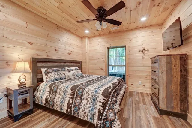 a bedroom with a large bed a flat tv screen and dresser