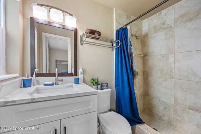 a bathroom with a granite countertop sink toilet a mirror and shower