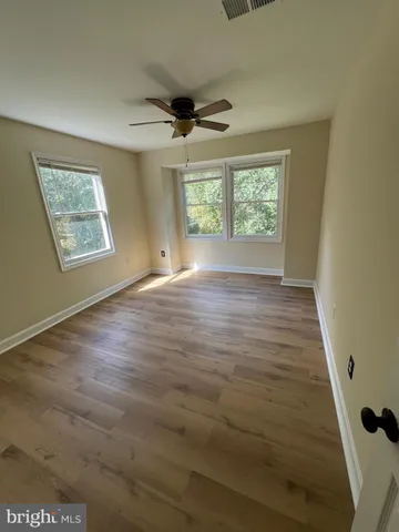 a view of an empty room with a window and wooden floor