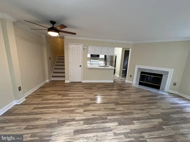 a view of kitchen and empty room with wooden floor