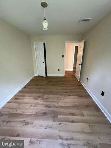 a view of an empty room with wooden floor and window