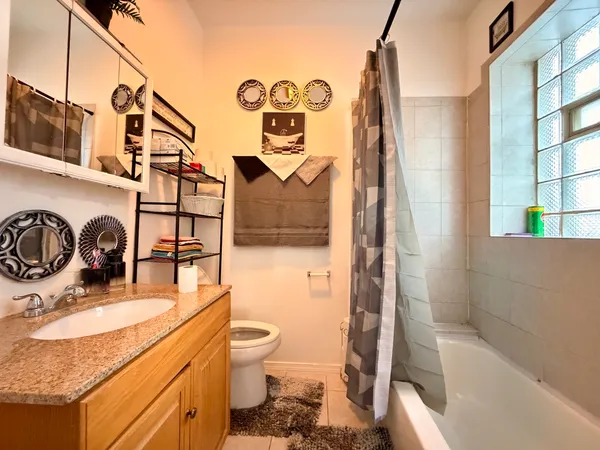 a bathroom with a granite countertop sink a toilet and shower