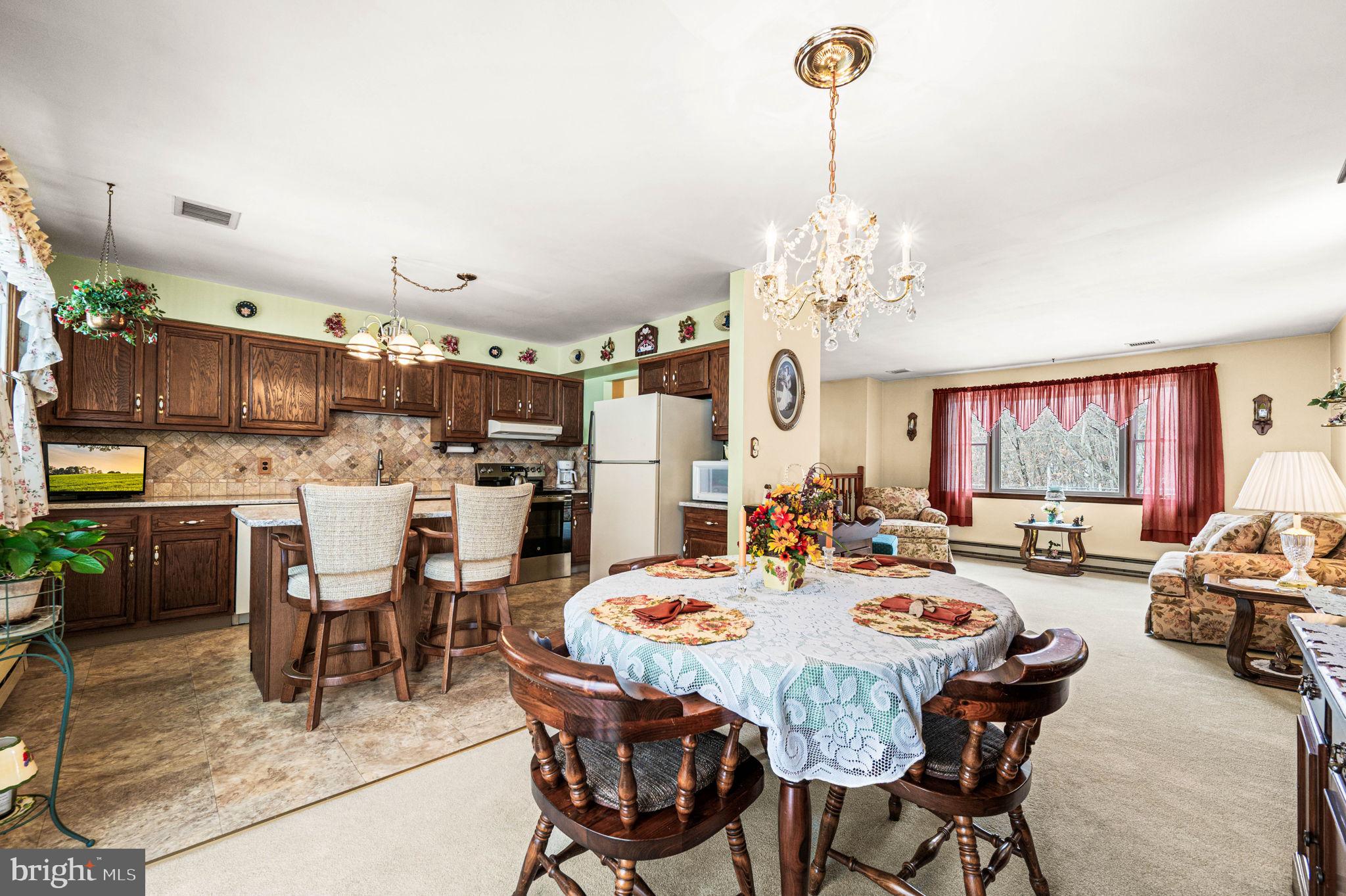 1548 County Line Road Bechtelsville, PA 19505 - Photo 9 of 31 a dining room filled with lots of tables a chandelier and kitchen view