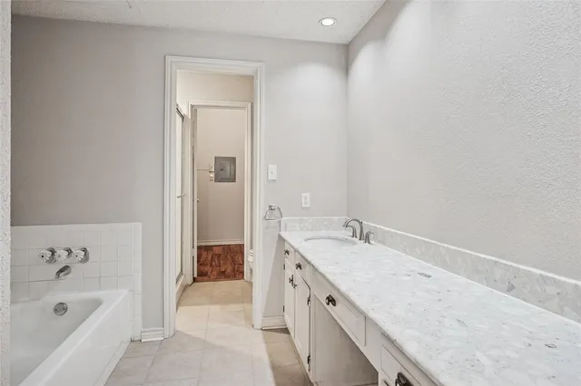 a bathroom with a granite countertop tub sink and mirror