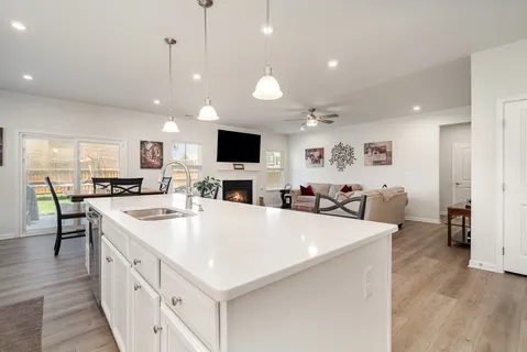a large white kitchen with a stove a sink a dining table and chairs