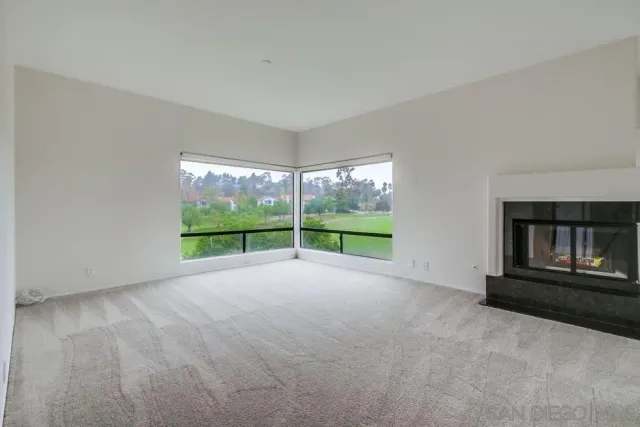 a view of an empty room with a fireplace and a window