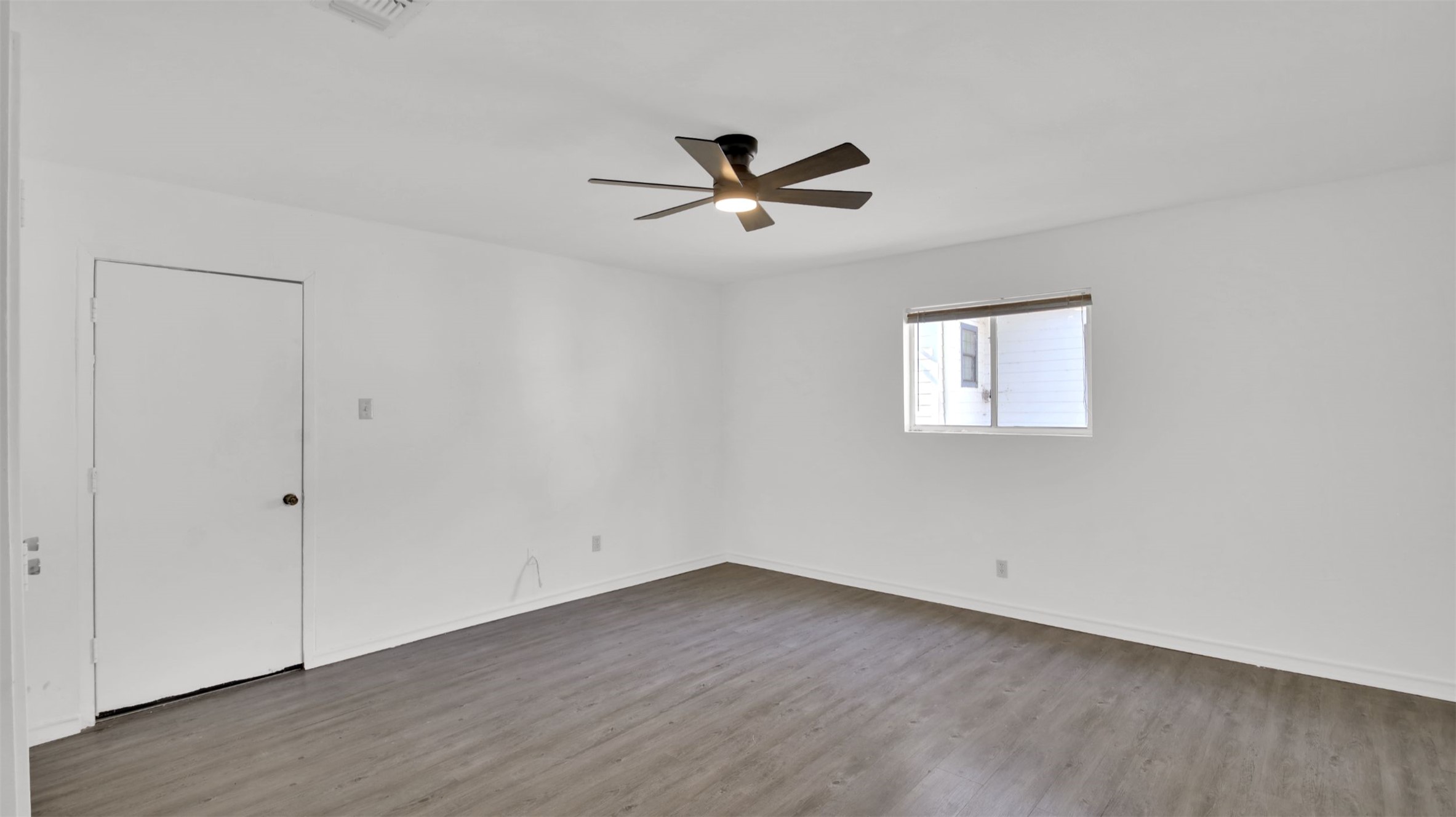 908 Tank Street Lockhart, TX 78644 - Photo 13 of 22 an empty room with wooden floor ceiling fan and windows