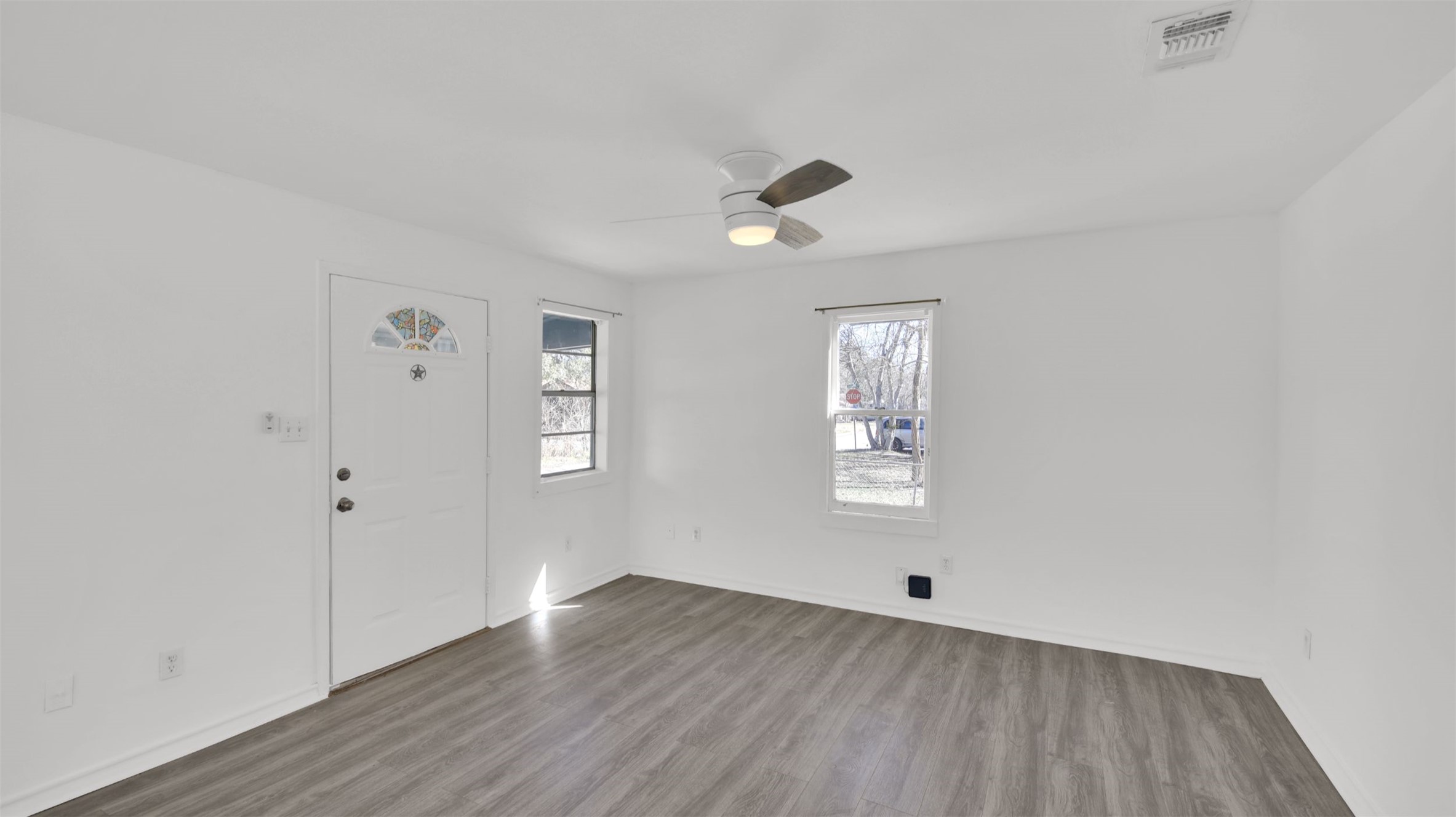 908 Tank Street Lockhart, TX 78644 - Photo 5 of 22 an empty room with wooden floor and windows
