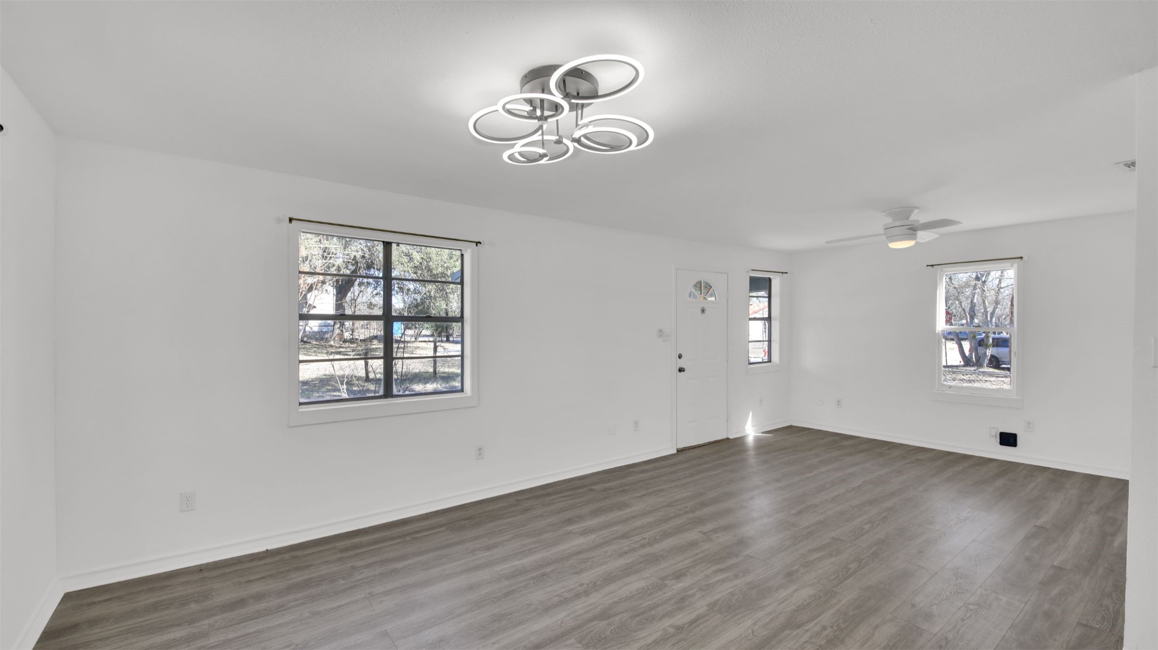 908 Tank Street Lockhart, TX 78644 - Photo 7 of 22 an empty room with wooden floor chandelier fan and windows