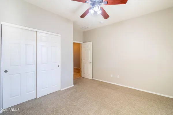 an empty room with a chandelier fan and windows
