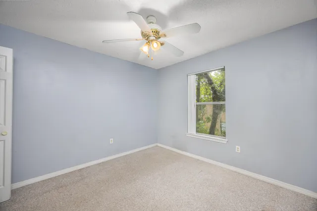 an empty room with a window and a ceiling fan