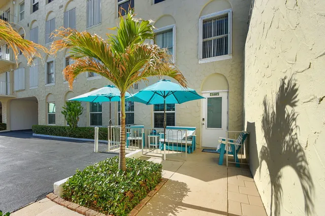 a view of a brick house with a yard and table and chairs under an umbrella