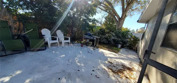 a view of backyard with table and chairs and a large tree