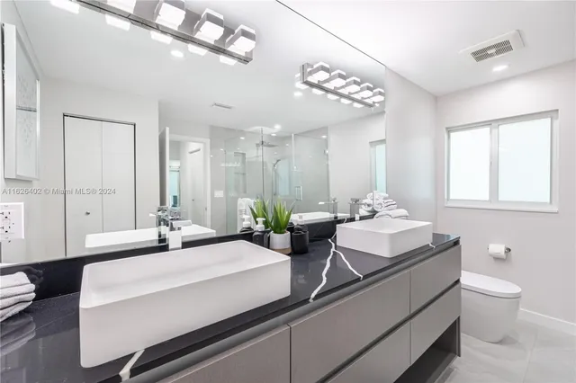 a bathroom with a double vanity sink mirror and toilet