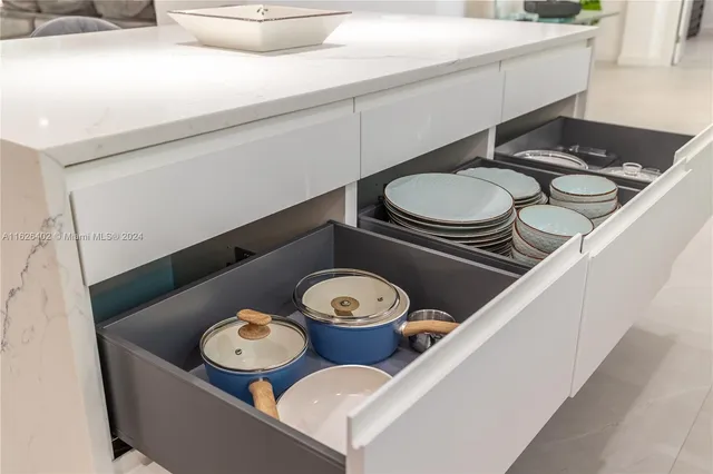 a table with white cabinets a stove and a sink