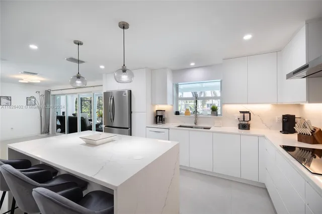 a large kitchen with kitchen island a stove a sink a center island and a refrigerator