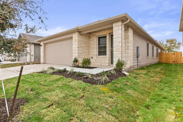 a front view of house with yard and trees in the background