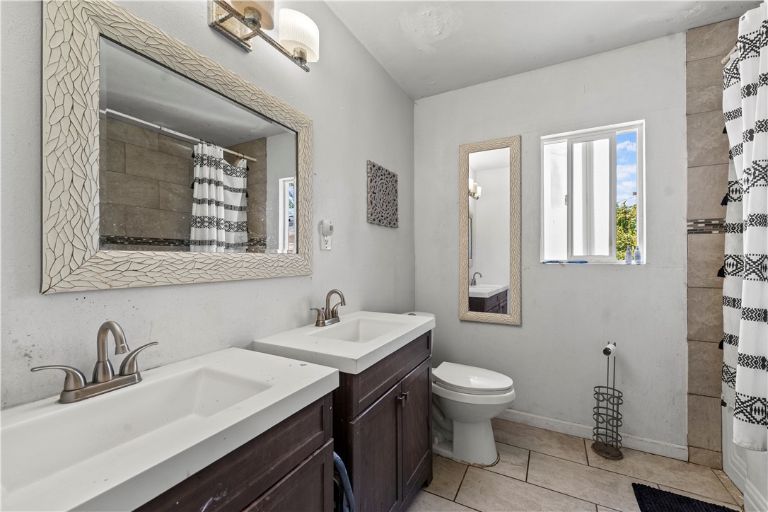 2725 East Tyler Street Carson, CA 90810 - Photo 8 of 30 a bathroom with a toilet a sink a mirror and a window