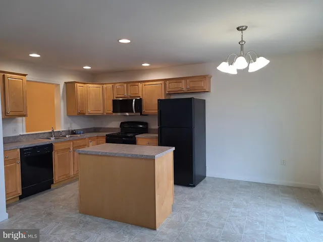 a kitchen with kitchen island granite countertop stainless steel appliances a refrigerator a stove top oven a sink and dishwasher