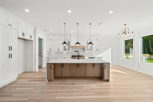 a view of an empty room with a window and kitchen area