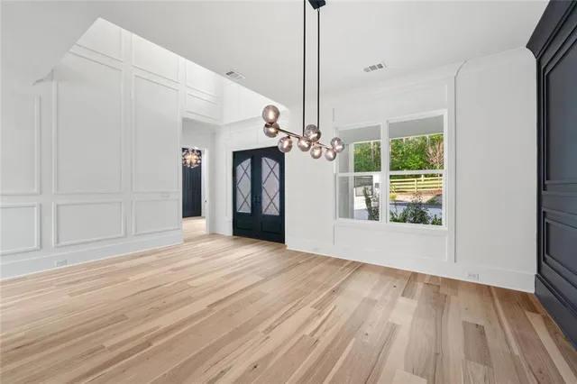 a view of an empty room with window and chandelier fan