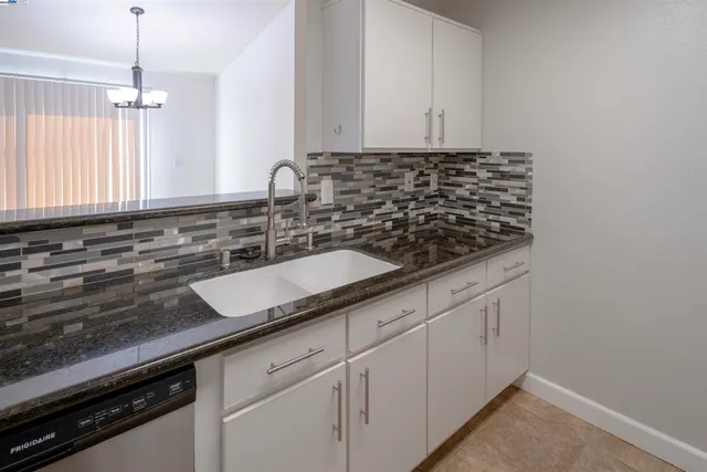 a kitchen with granite countertop a sink stove and cabinets