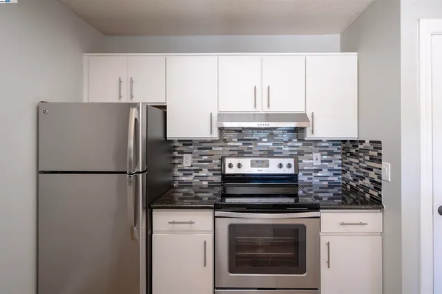 a kitchen with appliances a refrigerator and cabinets