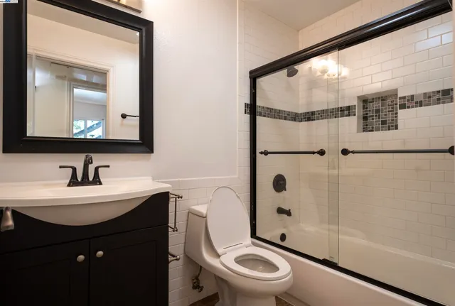 a bathroom with a toilet a sink a mirror and shower