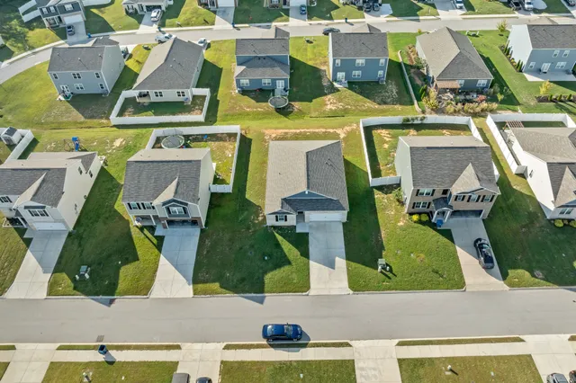 an aerial view of residential houses with outdoor space and trees