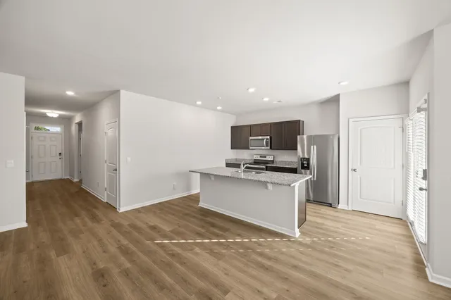 a large kitchen with stainless steel appliances granite countertop a stove a sink dishwasher a refrigerator and microwave with wooden floor