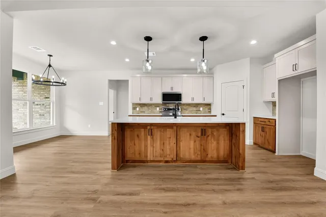 a kitchen with stainless steel appliances granite countertop a sink a stove and a wooden floors