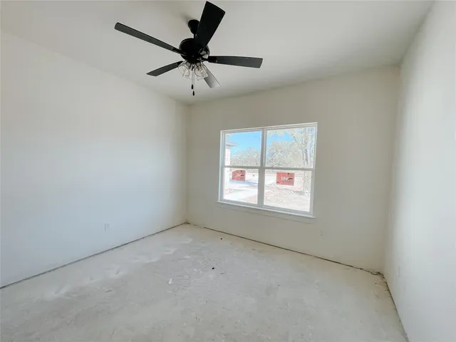 an empty room with a window and a fan