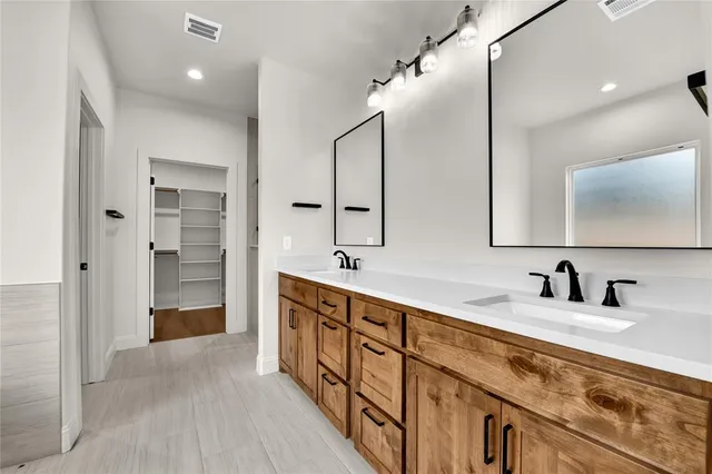a spacious bathroom with a double vanity sink a mirror and a bathtub
