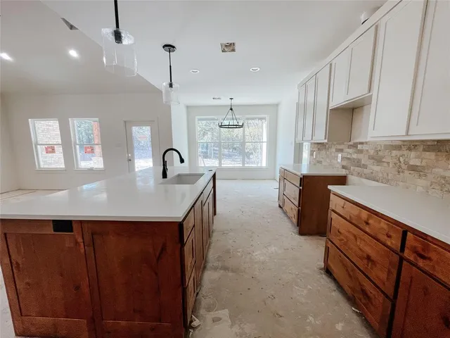 a kitchen with kitchen island granite countertop a sink window and cabinets