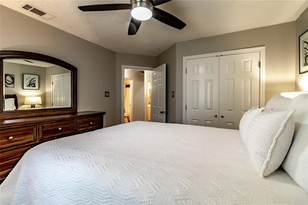 a bedroom with a bed couch and windows with wooden floor