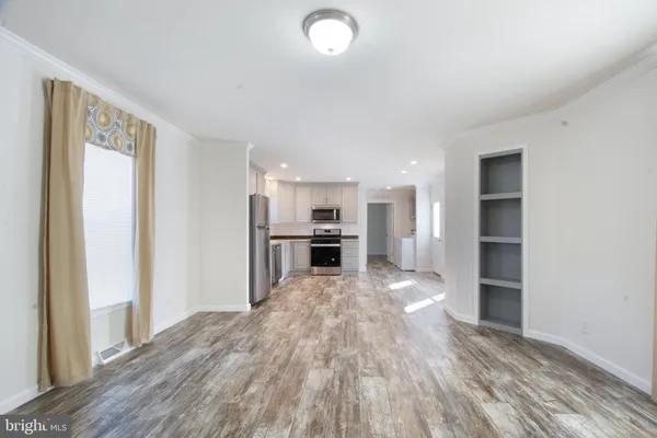 a view of kitchen and empty room with wooden floor