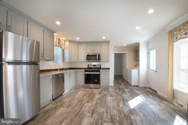 a kitchen with a refrigerator a stove top oven and wooden floor