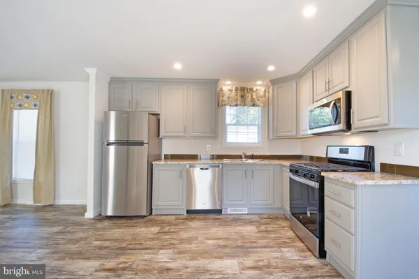 a kitchen with stainless steel appliances granite countertop a refrigerator a stove a sink and a microwave