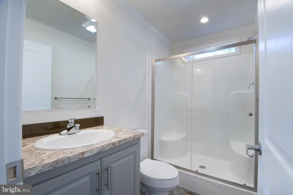 a bathroom with a granite countertop sink toilet a mirror and shower